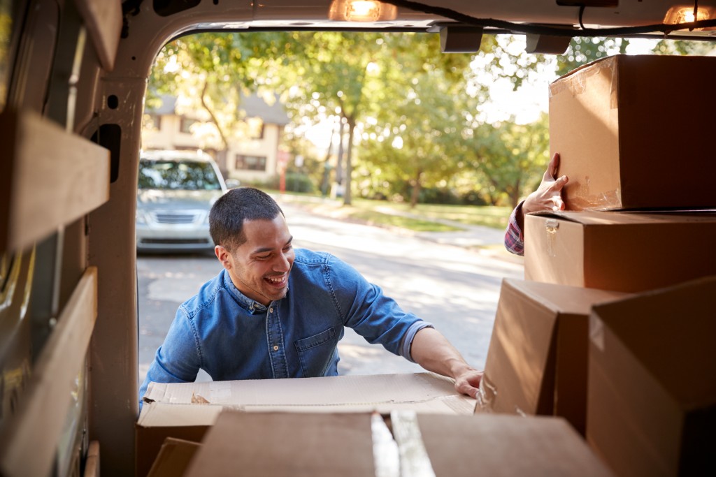 smiling man getting boxes from his car to his new home