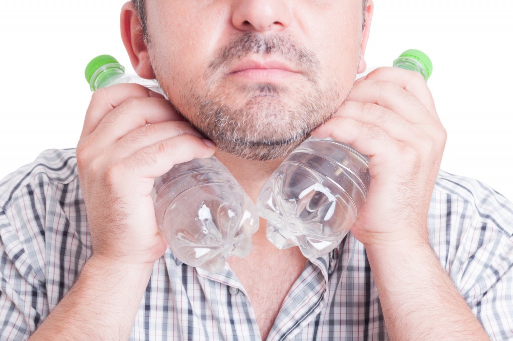 Man cooling his neck using cold water bottles