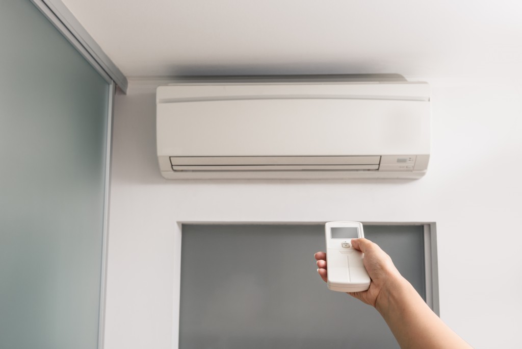 Hand With Remote Control Directed On The Air Conditioner in the room