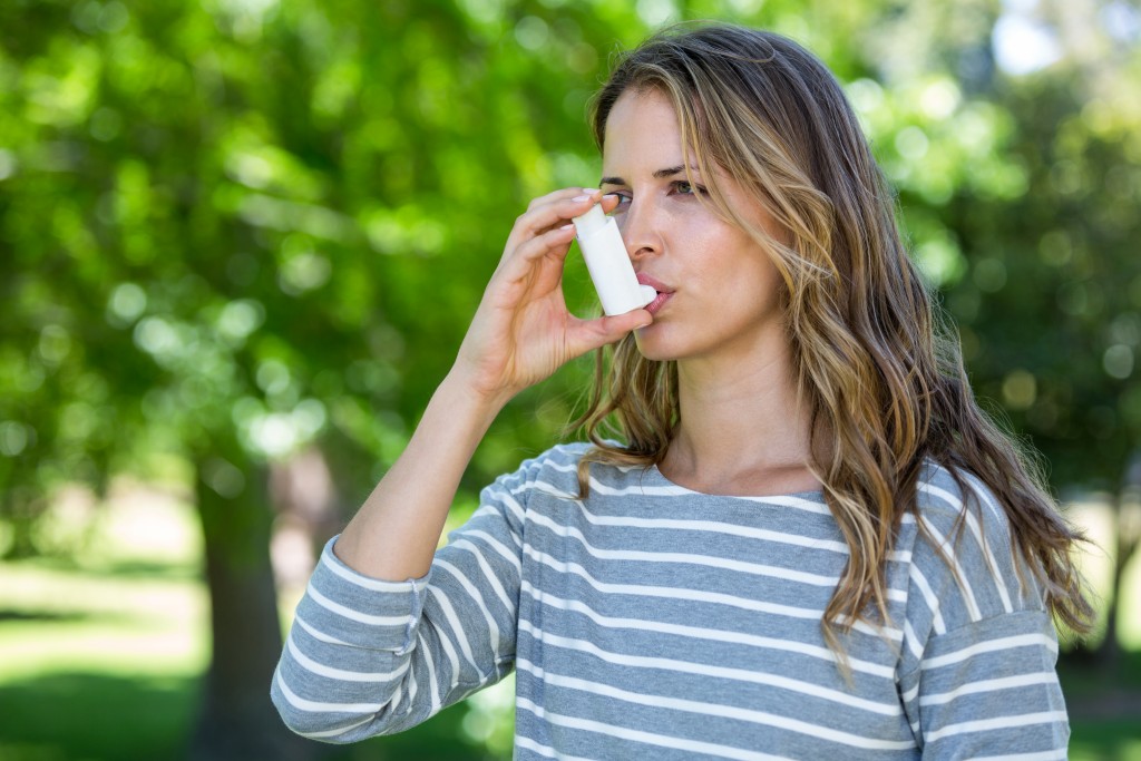 Woman taking her inhaler because of asthma