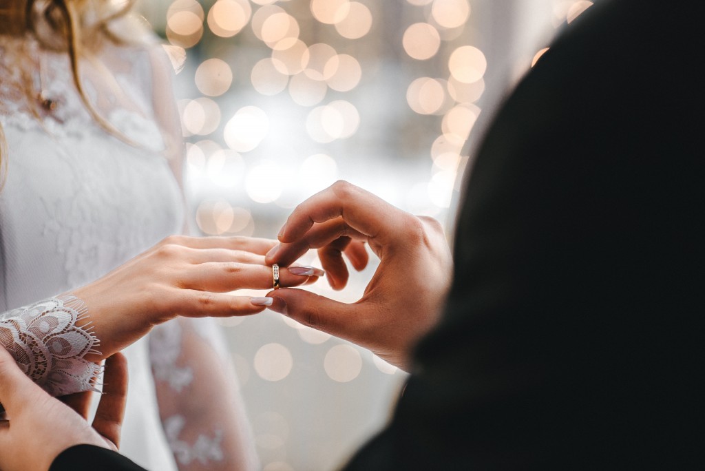 groom putting ring on bride's finger