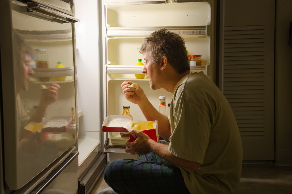 Man eating in front of the refrigerator