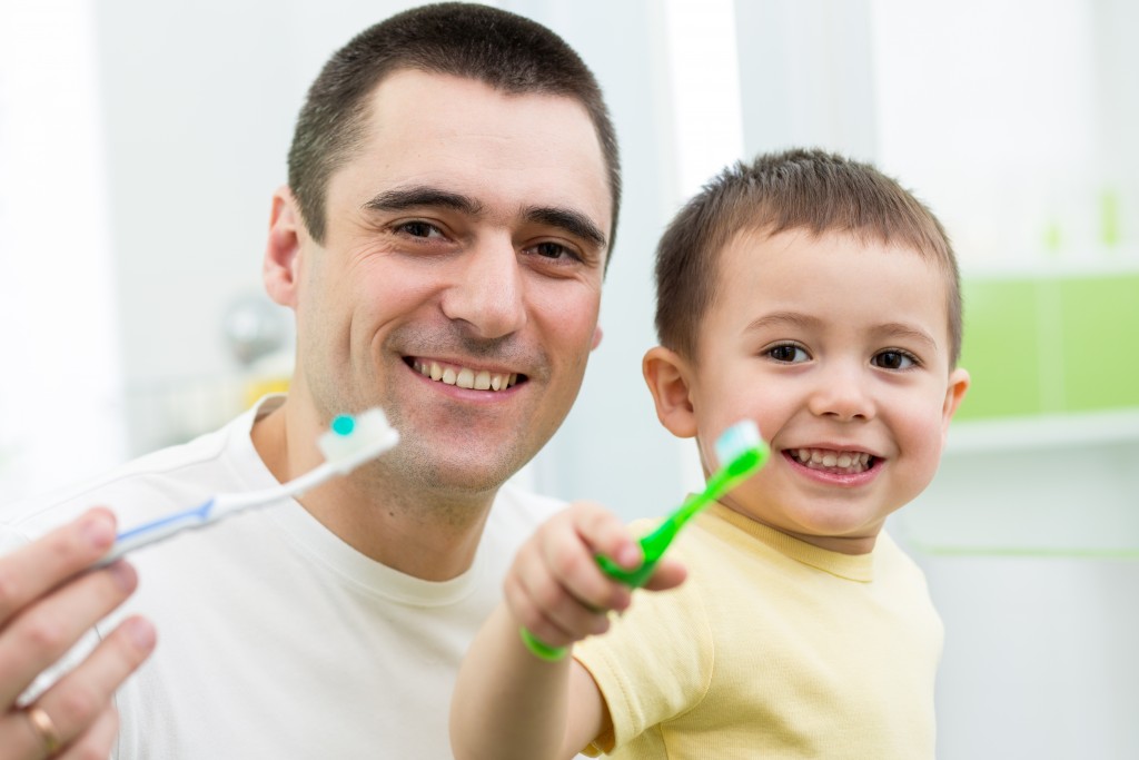 father and son brushing his teeth