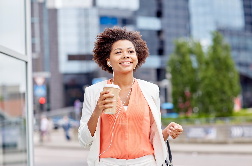 working woman walking confidently with coffee and music