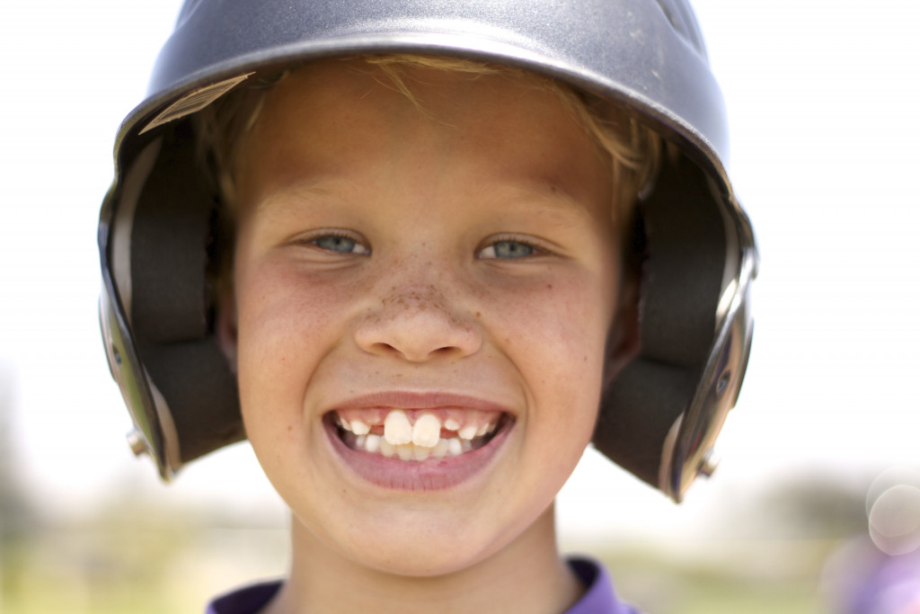 kid smiling with a baseball helmet