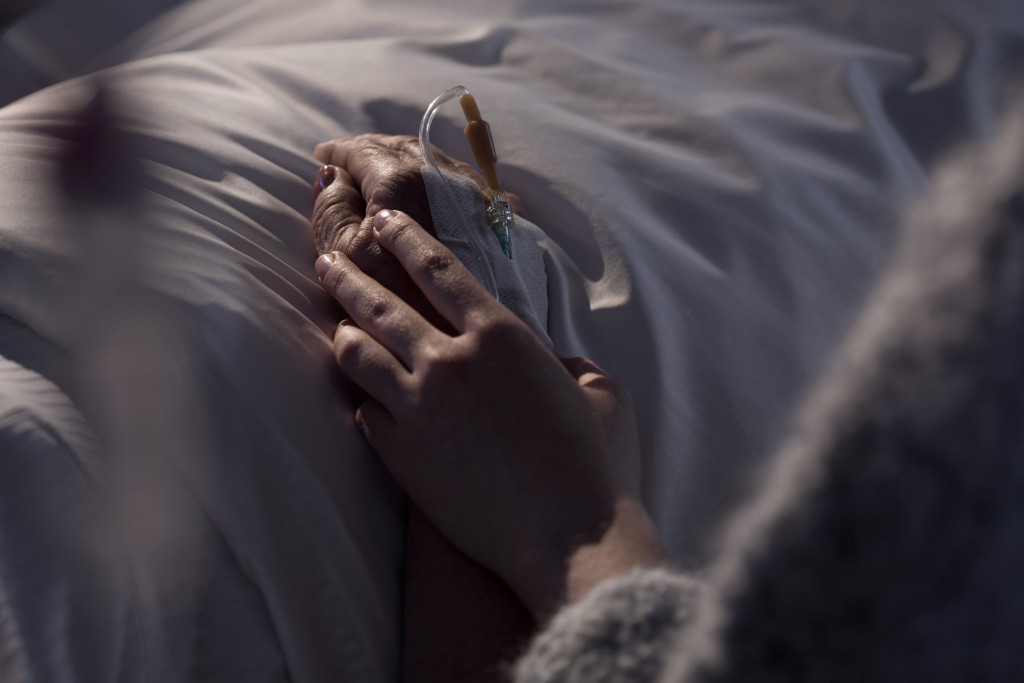 person touching loved one's hand lying in the hospital